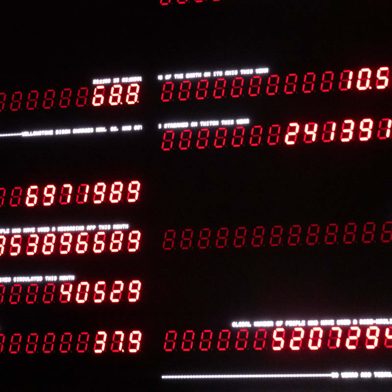 A dark photo with multiple lines of old fashioned seven-segement displays with red LEDs. Some lines are faintly lit whilst others show numbers.