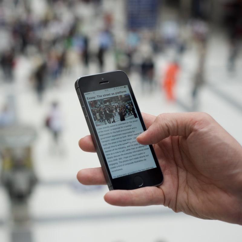 Photo of a hand holding a smartphone, which is showing a web article.