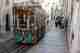 A funicular car descending a steep street in bright sunlight.