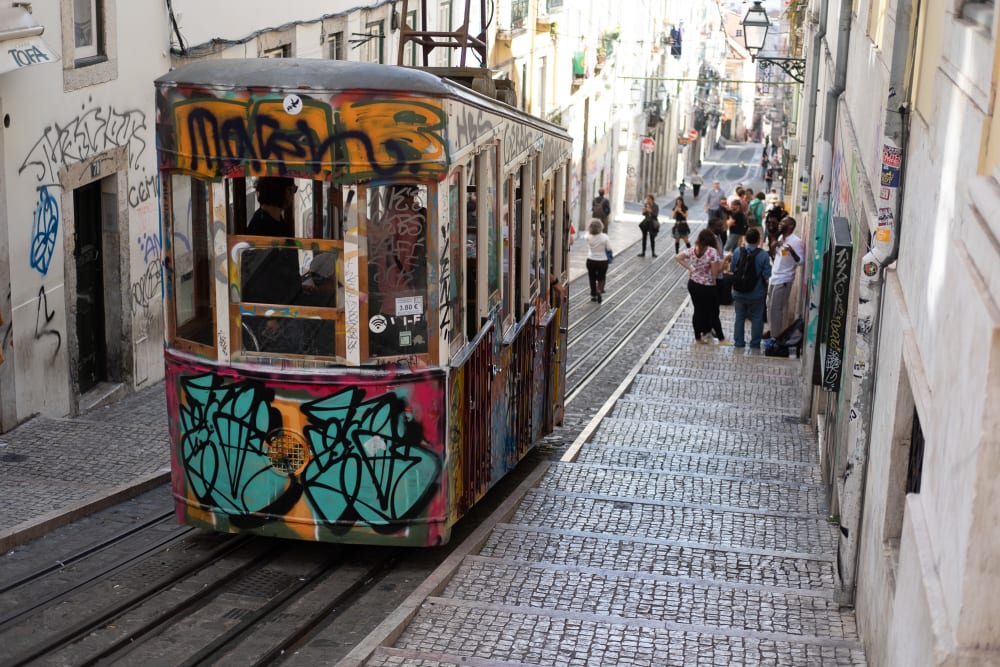 A funicular car descending a steep street in bright sunlight.