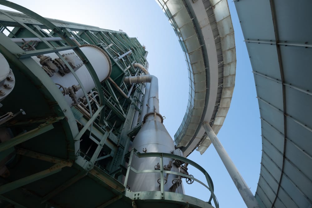 Looking directly up the Torre Galp from just inside the structure. The structure is painted in a light green-blue colour and made of many steel beams. On the right a walkway arcs around the frame.