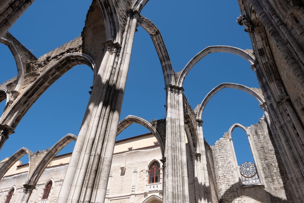 Looking up at the ruins of the Carmo Convent. All that remains are the arches of the building, with blue sky where the ceiling would be.