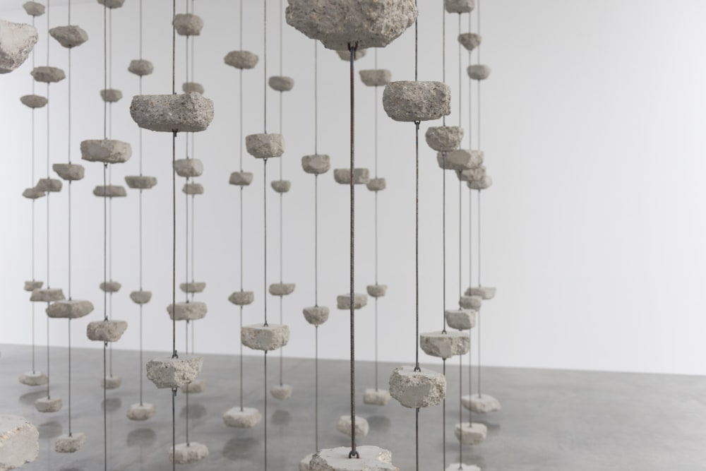 PIeces of concrete are suspended between lengths of steel in a regular grid pattern.