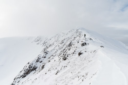 Ed in the distance looking down over a snow covered ridge.