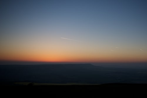 Twilight over the South Downs. The sky is clear with yellow and orange hues on the horizon.
