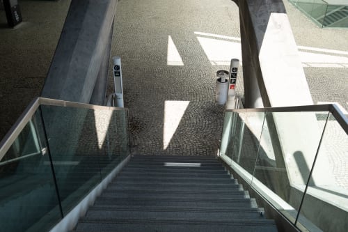 Looking down a staircase in a train station. The base of the stairs has an irregular tiled pattern.