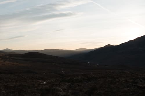 A photo of a valley in Torridon, just before sunrise. The sky is bright, but the land very dark still.