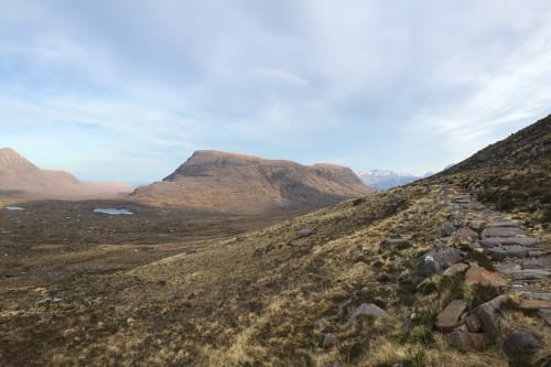 Panorama from side of Beinn Eighe. The landscape is brown with patches of green in a partially sunny day.
