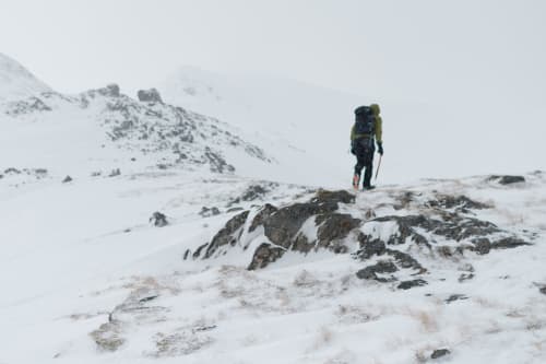 Chris walking ahead up a snowy mountain - there’s low visibility and a few flakes of snow in the air.