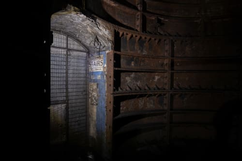 Dimly lit doorway with sign to stairs and metal bulkheads to the side.