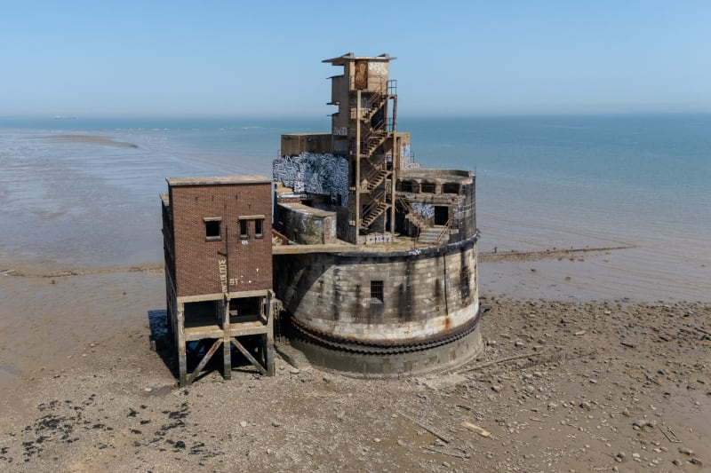 Exterior photo of the battery showing a rectangular structure on stilts on the left, and a larger cylindrical structure on the right.