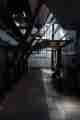 Looking straight on in the interior of the Maat engine room. there’s a large boiler to the left and tall windows in the background. Black pipes descend from above.