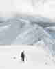 Chris walking ahead of camera, with several snowy mountains ahead of him.