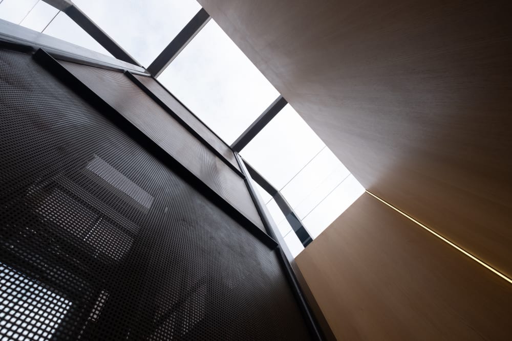 Looking up at a wooden stairwell with large skylight.