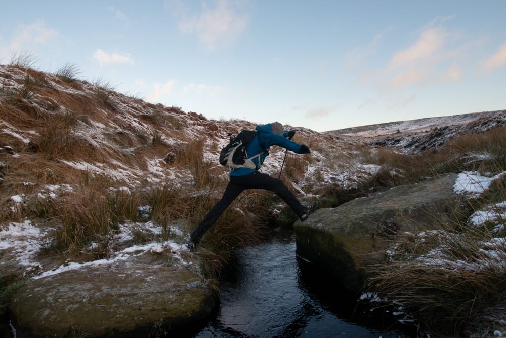 Ed Horsford mid leap whilst crossing a small stream.