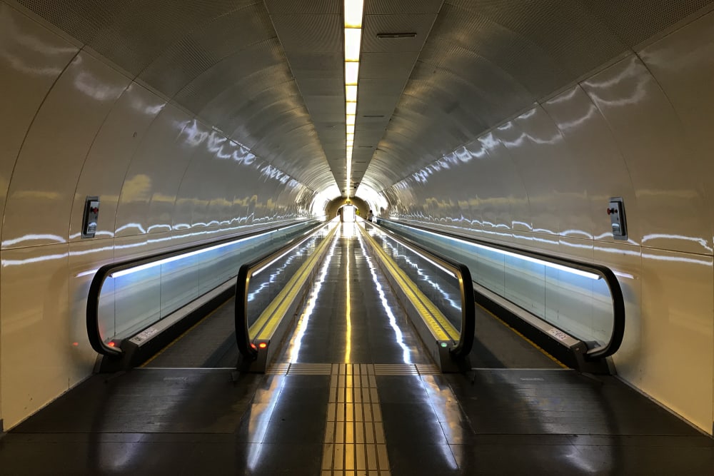 A photo looking down a long corridor with two moving walkways on either side.