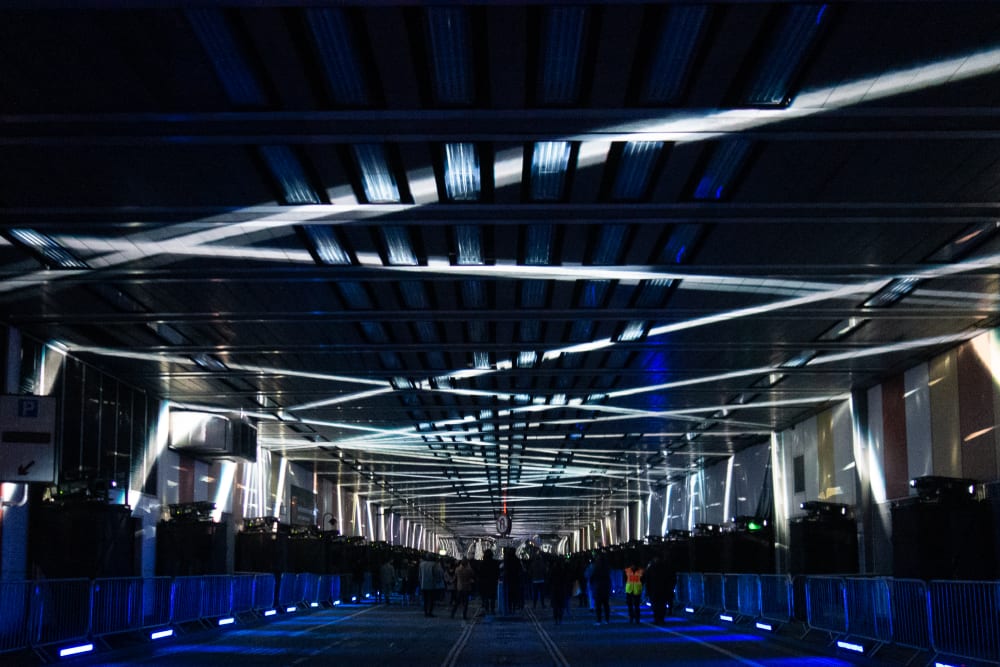 A photo looking straight down the covered Beech Street. The photo is dark, with white criss cross lights on the ceiling, receding into the distance.