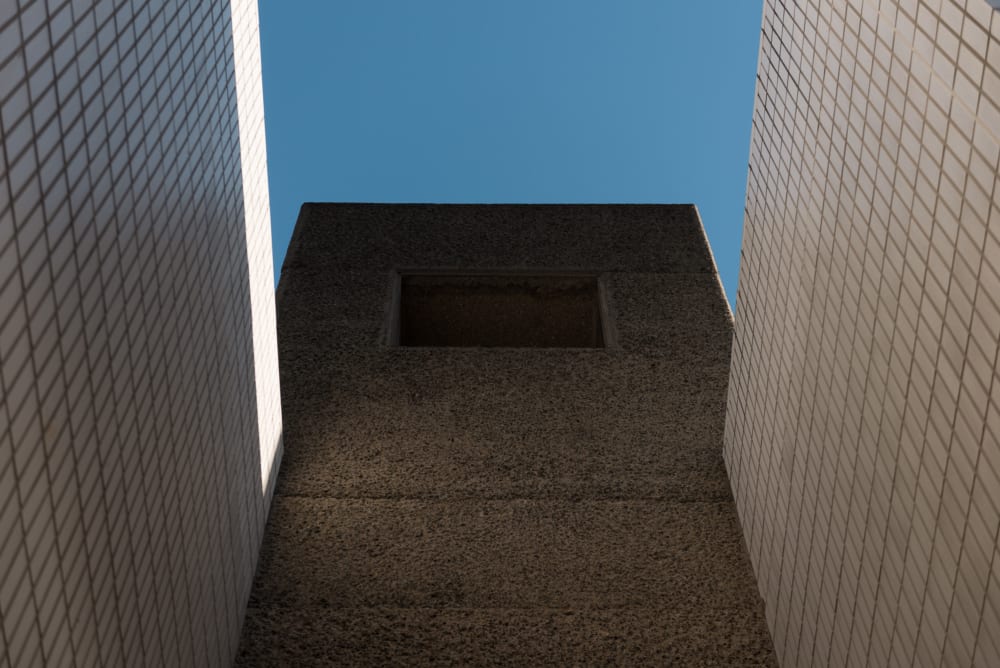 A photo of an exterior wall in the Barbican. The wall is pebbledash concrete. On the left and right side are white tiles.