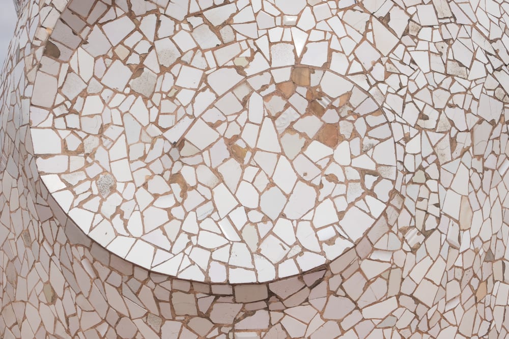 A close photo of a mosaic at Casa Milà. The tiles are roughly broken and all white - they’re arranged in a spiral pattern.