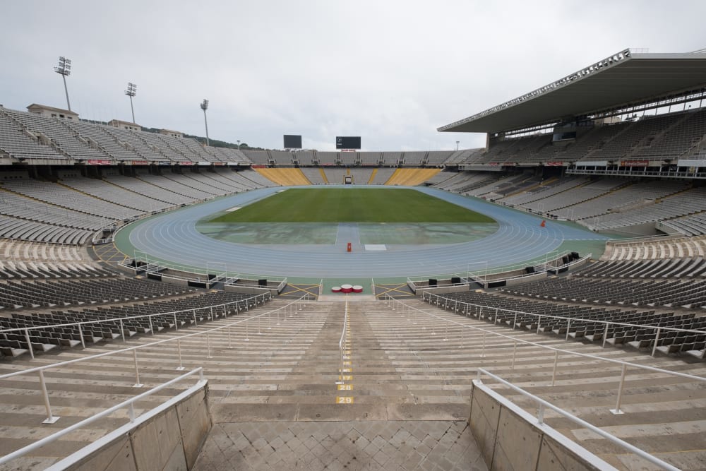 A photo of the olympic stadium in Barcelona. The photo is taken from one end, looking in to the main arena. There are seats all around and the playing field in the centre.