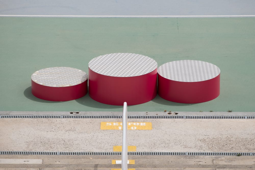 A photo of the winners podium at the Barcelona olympic stadium. The podium is made of three red cylinders of different heights.