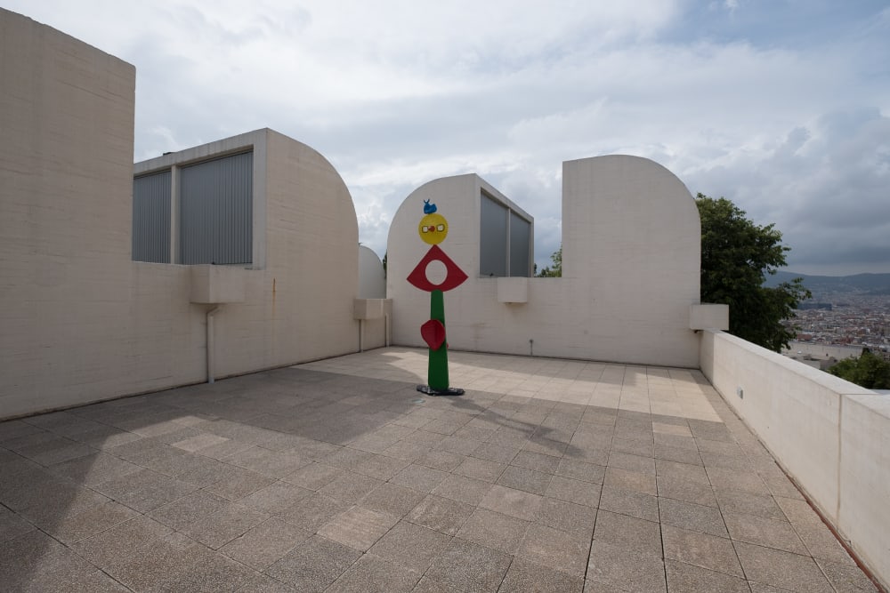 A photo taken on the roof of the Joan Miró Foundation. There are white walls on the side, some with rounded corners. There’s an abstract coloured sculpture in the centre of the terrace.