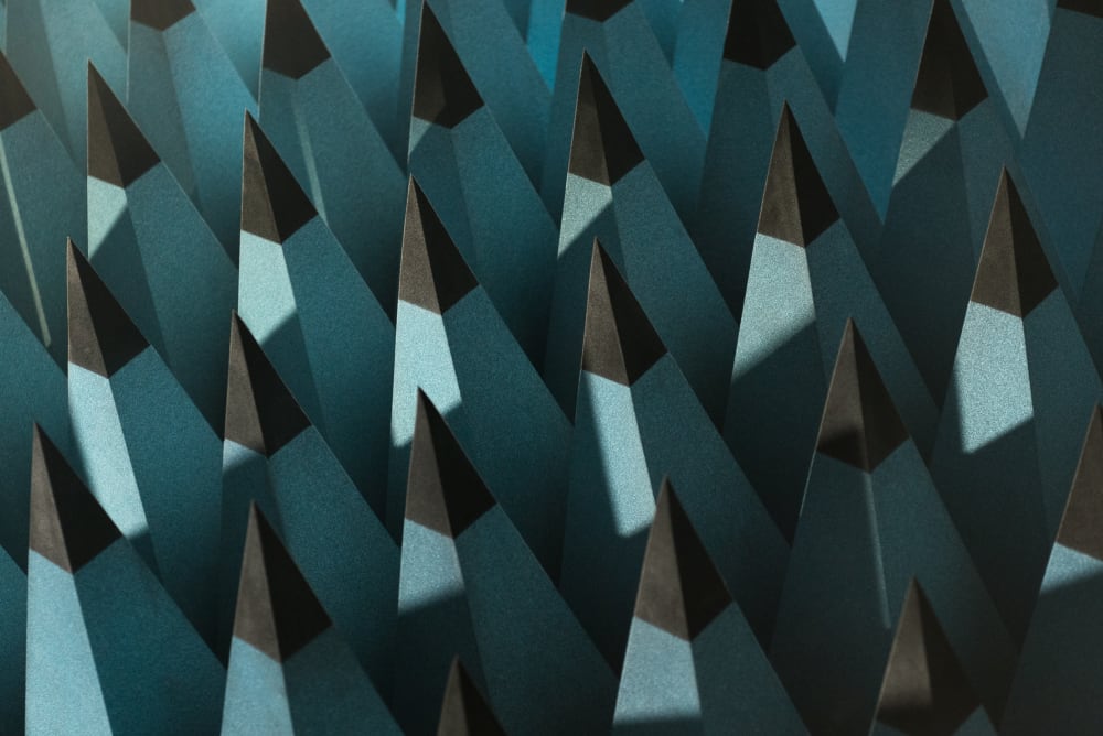 A close photo of some radio-wave insulating foam. The foam is formed in to tall pointy pyramids with pale blue bases and black tips. The pyramids are arranged in a rigid grid - as if the entire floor were spikey.