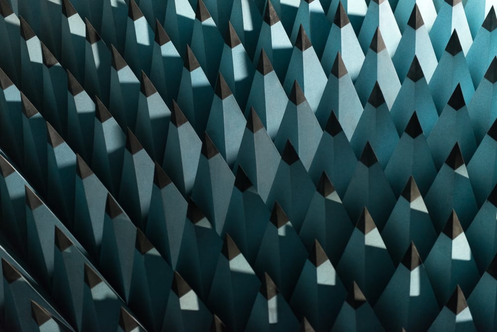 A photo of some radio-wave insulating foam. The foam is formed in to tall pointy pyramids with pale blue bases and black tips. The pyramids are arranged in a rigid grid - as if the entire floor were spikey.