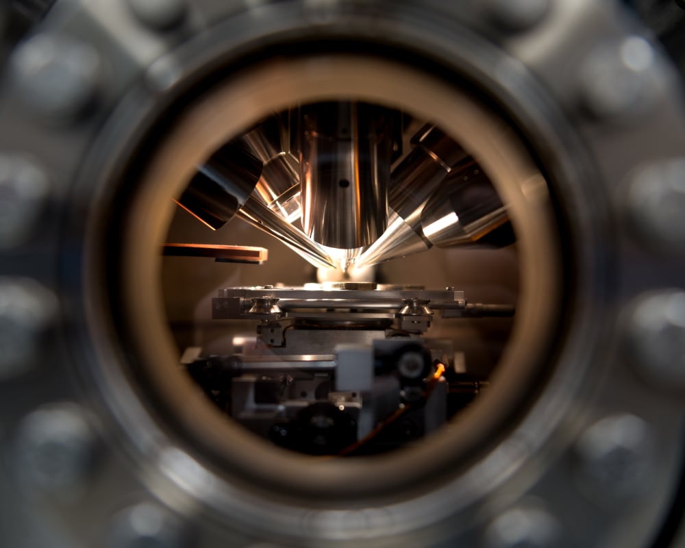 A macro photo through a circular window looking at several sensing instruments pointing at a coin.