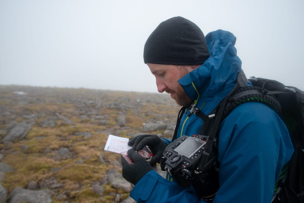 Ed looking down at a compass held precisely on a map.