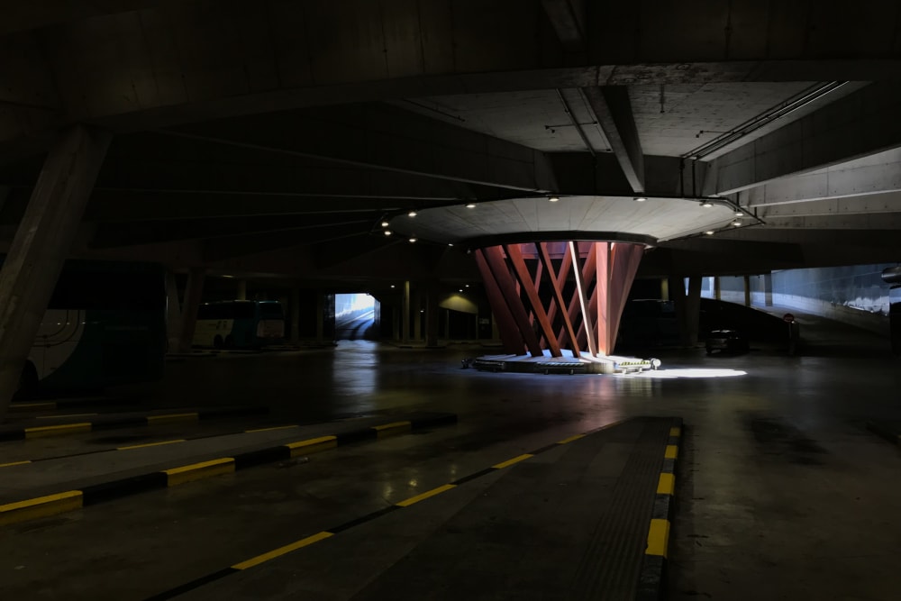 Inside the San Sebastián bus station. The loading bay is large and dark, with a circular sculpture in the middle, letting light in from above.