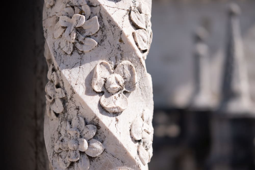 A close detail shot of an aged carved marble pillar in the Torre de Belém. The column has a spiral shape with fine flowers carved at regular intervals.