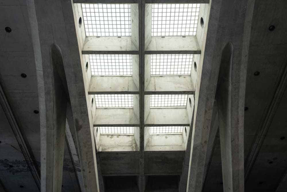 Looking up at skylight windows in a train station. The ceiling is cast concrete, and the lights are made from a grid of glass tiles.