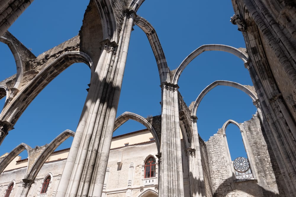 Looking up at the ruins of the Carmo Convent. All that remains are the arches of the building, with blue sky where the ceiling would be.