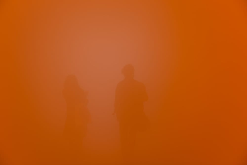 A deep orange frame with no distinct features. Two bodies can just be seen in the background.