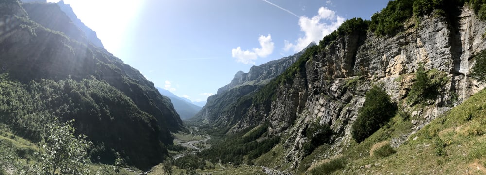A wide panorama of a valley with steep rocky sides.