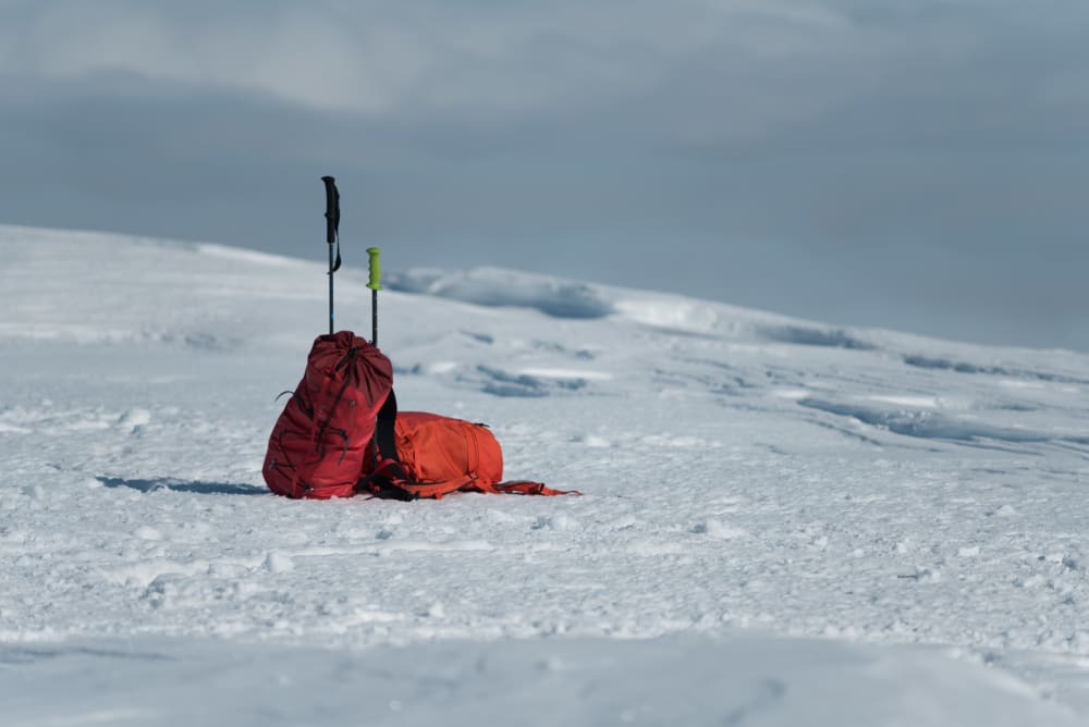 Two climbing bags lean against each other - deserted on a snowy plateau.