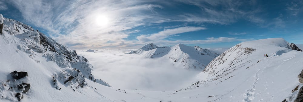 A panorama taken from Aonach Mòr looking towards Ben Nevis. The sky is sunny and deep blue, and there’s a cloud inversion, so the ground isn’t visible.