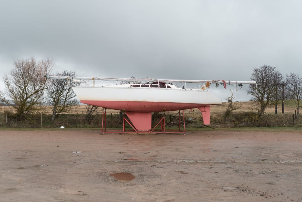 Looking side on to a small boat on stilts out of water.