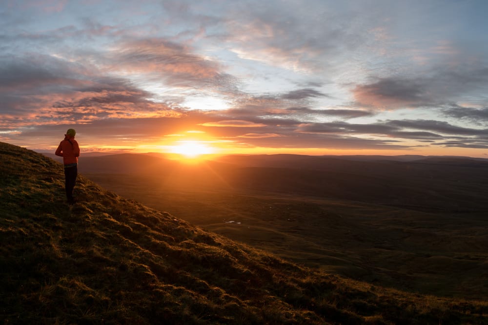 Ed stands alone at sunrise looking out over the golden hills.