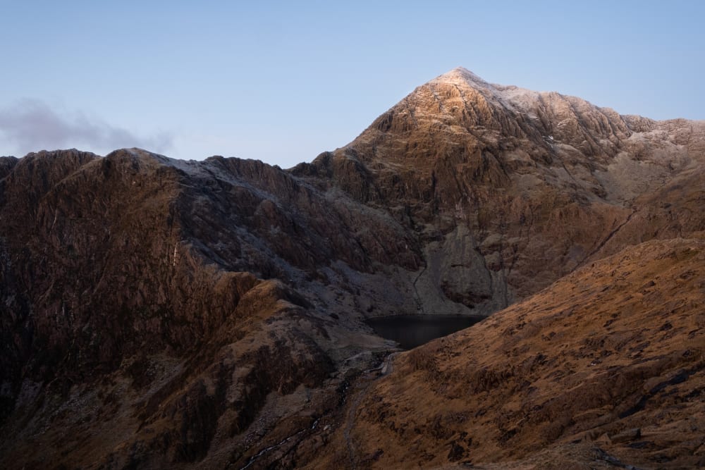 The jagged face of snowdon before sunrise. The mountain has a light dusting of snow on the top.