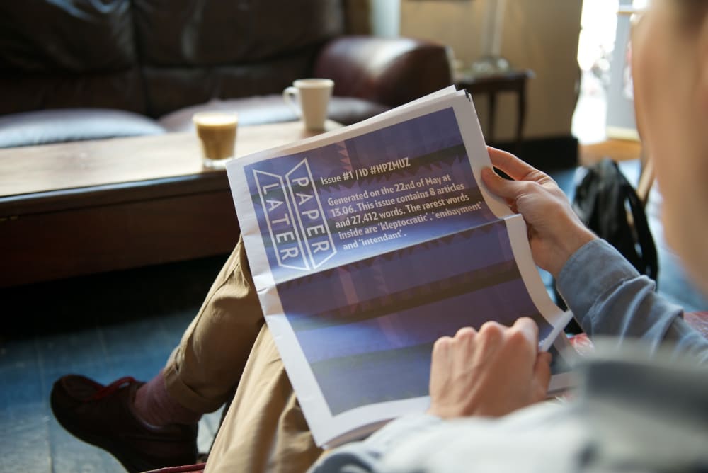 A man reading a PaperLater newspaper in a coffee shop.