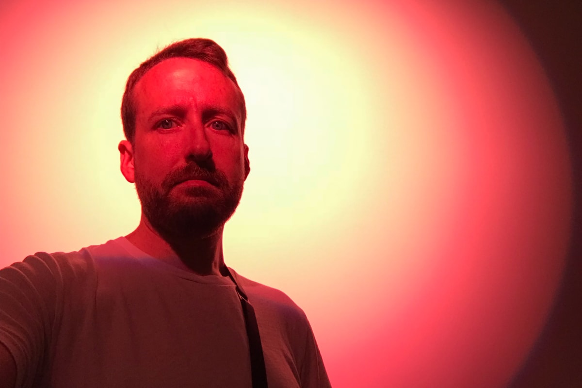 A self portrait of Ed Horsford. There’s a very bright red spotlight next to his head on the wall behind.