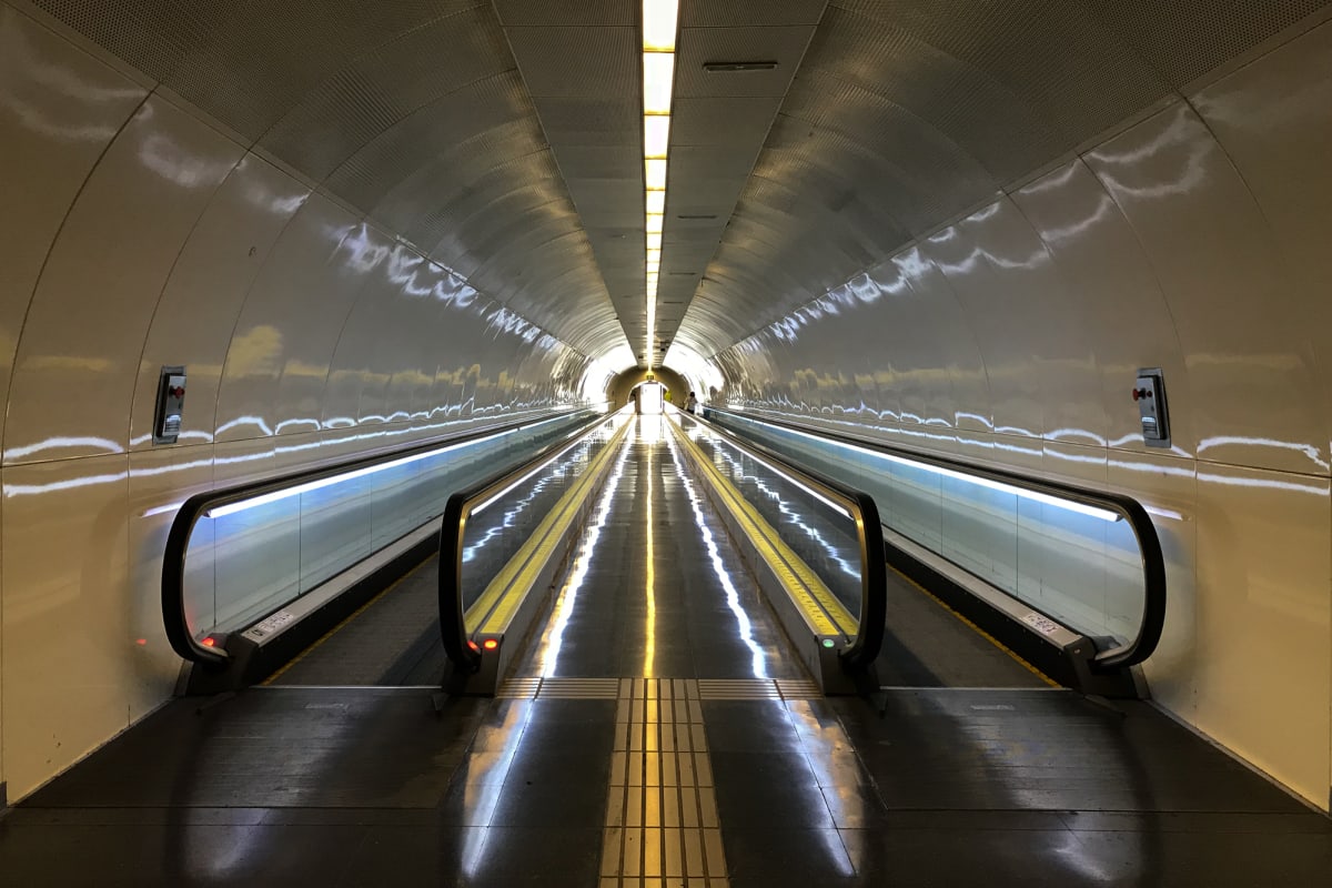 A photo looking down a long corridor with two moving walkways on either side.