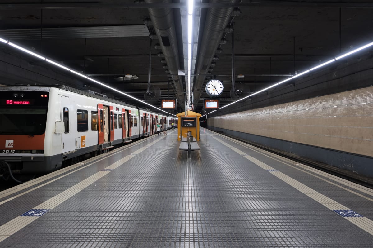 Looking straight down a train platform, with tracks on either side. There’s a train on the left hand side.