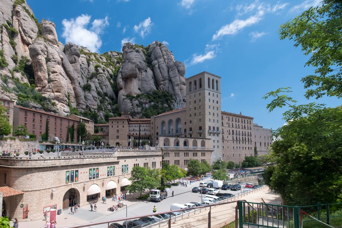 A view of the town of Montserrat. The cathedral is in the foreground, with mountains looming behind.
