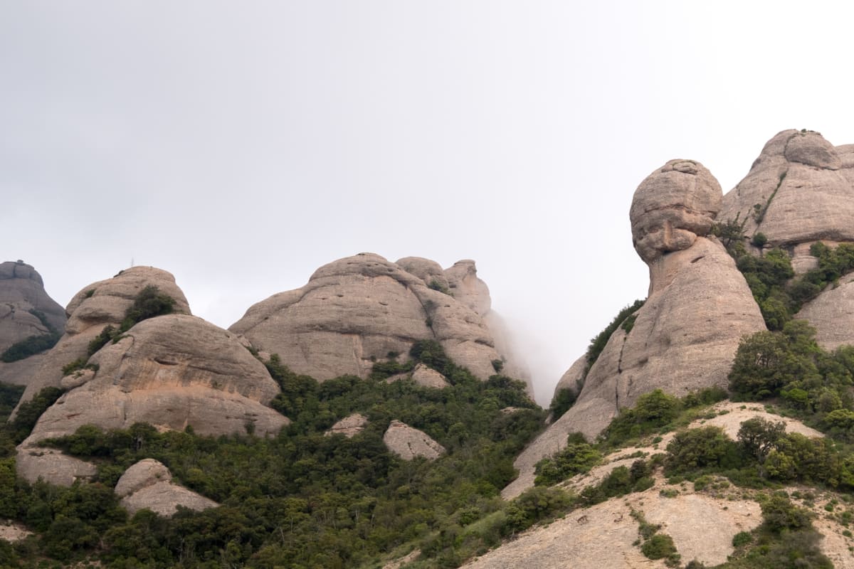 Looking up at the peaks of some mountains in Montserrat. The rocks are bulbous and separated like molten lumps.