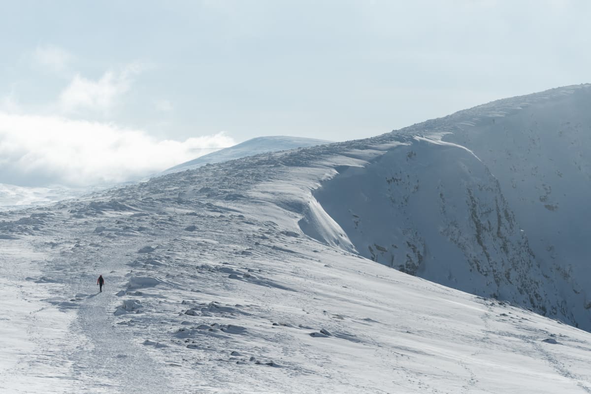 A photo of Ed walking in the distance up a snowy mountain.