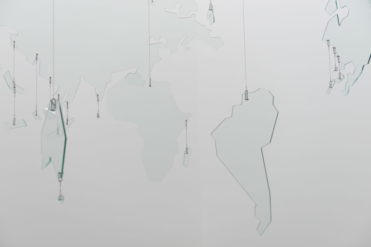 A large mobile made from sheets of glass cut in to shapes of continents, forming a glass map of the world.
