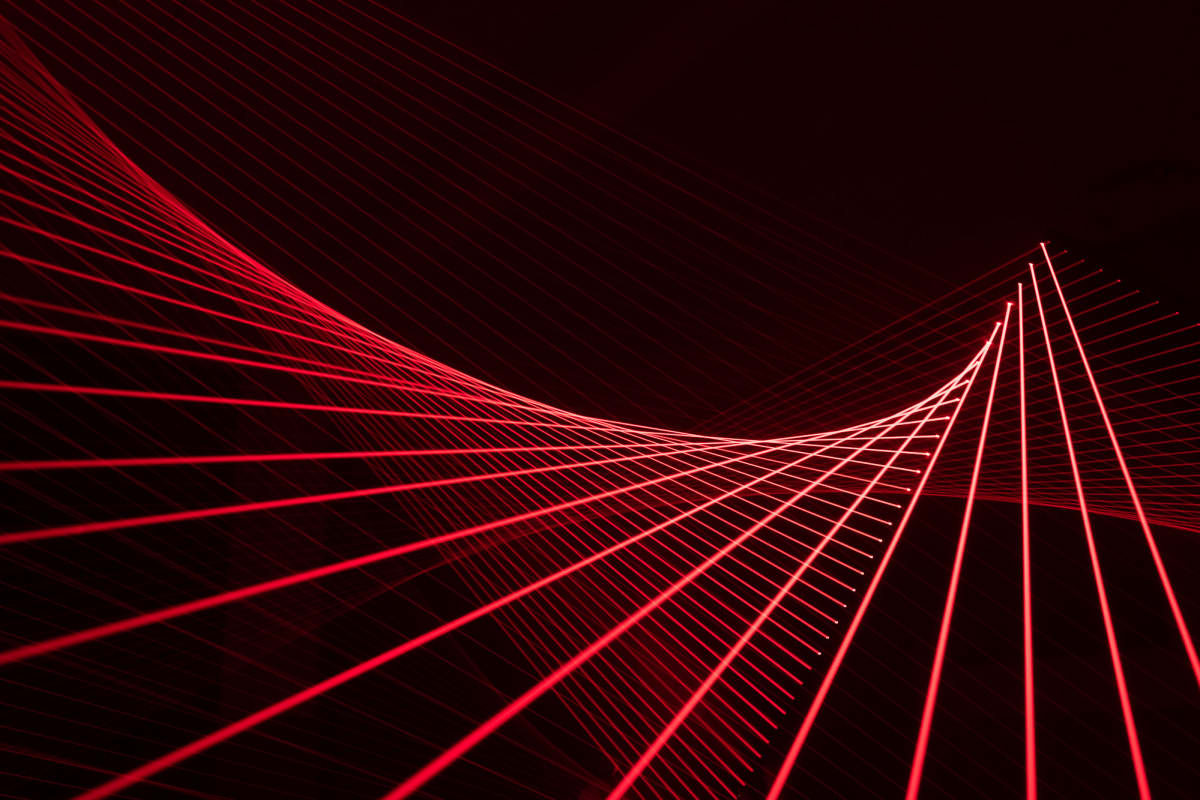 Red lasers in a dark room form lines at regular angles, sweeping a curve to the left.